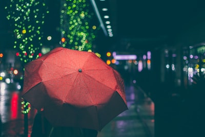 人红雨伞走在街头在夜间
